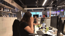 a woman sits at a desk with a bottle of aquafina water in front of her