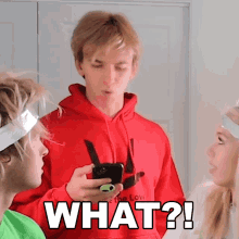 a man in a red hoodie is holding a cell phone and the word what is on the bottom