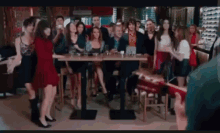 a woman in a red dress is dancing in front of a group of people in a bar .