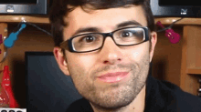 a man wearing glasses and a black shirt is smiling in front of a dell computer