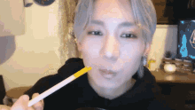 a man with gray hair is holding a yellow stick in his mouth