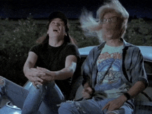 a man wearing a shirt that says aerosmith is sitting next to another man