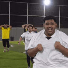 a group of men are playing soccer on a field and one of them is wearing a qatar shirt