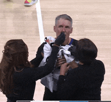 a man with a towel wrapped around his nose is being helped by two women