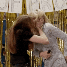 two women are kissing in front of a sign that says prom