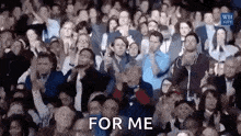 a large crowd of people are applauding in a stadium and the words `` for me '' are visible in the foreground .