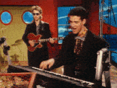 a man playing a guitar next to a man playing a keyboard