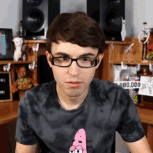 a man wearing glasses and a tie dye shirt stands in front of a sign that says 900,000