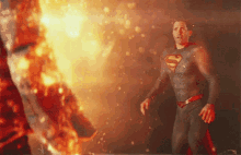 a man in a superman suit is standing in front of a large fire