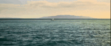 a boat is floating in the ocean with mountains in the background