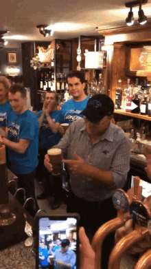 a group of men wearing blue shirts that say lions are standing around a bar