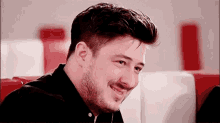 a man with a beard is smiling and looking at the camera in a diner .