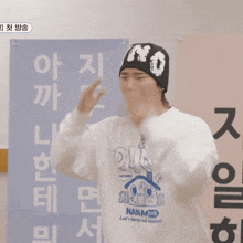 a man wearing a nanao shirt is covering his eyes with his hands