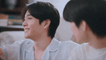 a man in a blue shirt smiles while sitting next to another man