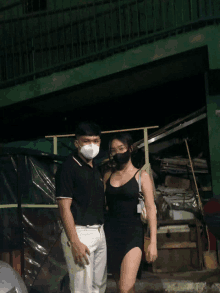 a man and a woman wearing face masks stand in front of a building