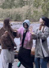 a woman in a purple sweater is jumping in the air while standing next to two other women