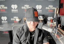 a man wearing a hat is sitting in front of a pop culture wall
