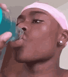 a man wearing a pink headband is drinking a blue beverage from a bottle .
