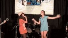 two women are dancing on a stage in front of a banner that says battle of the bands