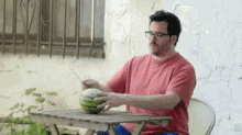 a man is sitting at a table with a watermelon on it .