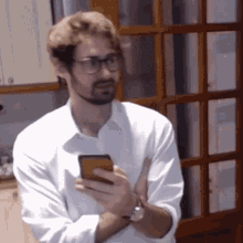 a man wearing glasses is holding a cell phone in his hand