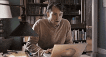a man is using a laptop computer in a library .