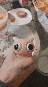 a person is holding a toy in their hand with big eyes