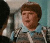 a young boy with a backpack is talking to another boy .