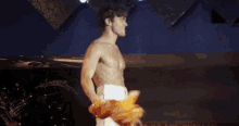 a shirtless man is walking on a stage holding a towel in his hand .