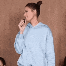 a woman wearing a light blue hoodie with the letters ap on it