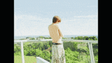 a shirtless man stands on a balcony overlooking a lush green valley