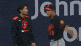 a baseball player wearing a black jersey with the letter b on it