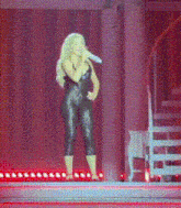 a woman singing into a microphone while standing on a stage