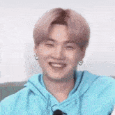 a close up of a person wearing a blue hoodie and smiling with their eyes closed .