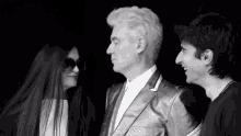 a woman wearing sunglasses looks at a man in a silver suit