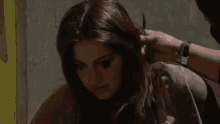 a woman with long hair is getting her hair done by a man .