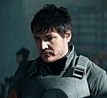 a man with a beard is wearing a gray armored vest