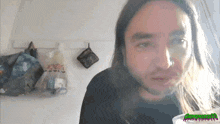 a man with long hair and a beard is looking at the camera with a green watermark that says ' swamp monster '