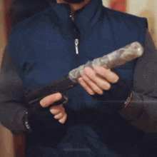 a man in a blue vest is holding a gun in his hands