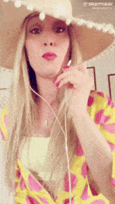 a woman wearing a straw hat and a yellow shirt with a starmaker logo