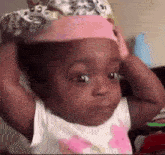 a baby wearing a pink headband is making a funny face .