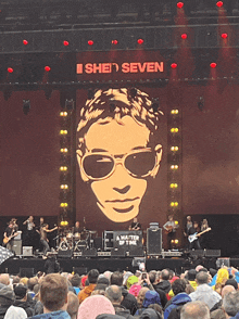 a group of people are sitting in front of a stage that says she seven