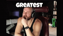 a man wearing headphones is sitting in a chair with the words greatest written above him