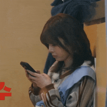 a woman is holding a cell phone in her hand with a red letter u in the background