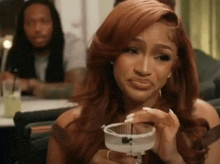 a woman is holding a martini glass and making a face .