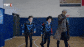 three boys are running in a gym with trt1 written on the bottom of the screen