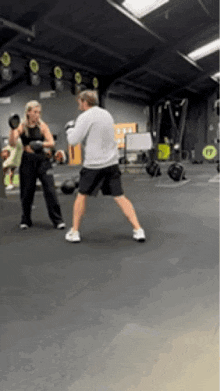a man and a woman are boxing in a gym and the woman is wearing boxing gloves .