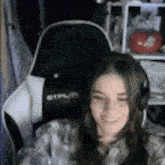 a young woman wearing headphones is sitting in a gaming chair .