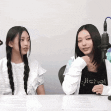 a girl wearing a jichol shirt sits at a table