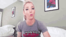 a woman wearing a grey shirt that says work bitch